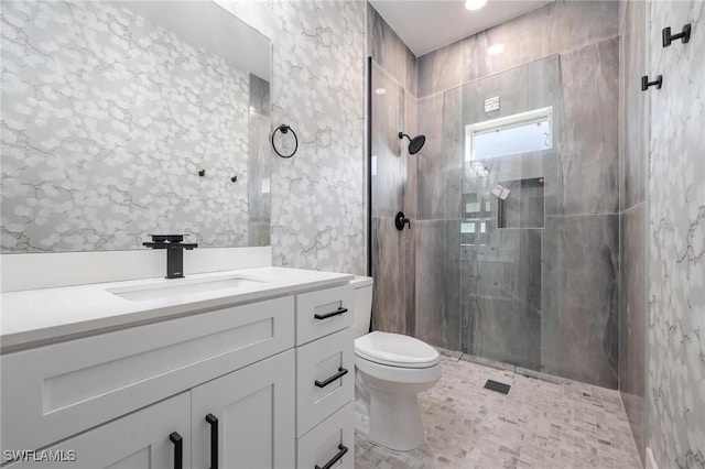 bathroom featuring a tile shower, vanity, and toilet