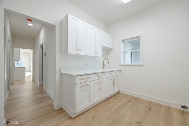 kitchen featuring light wood-type flooring, white cabinetry, and sink