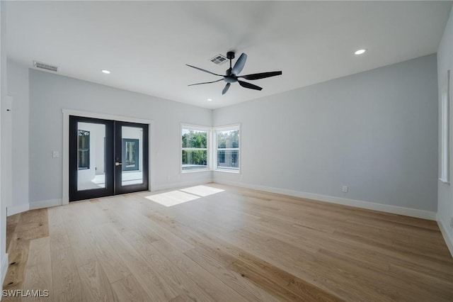 empty room with ceiling fan, light wood-type flooring, and french doors