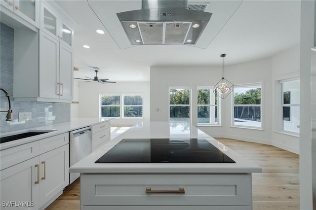 kitchen featuring black electric stovetop, white cabinetry, a kitchen island, and sink