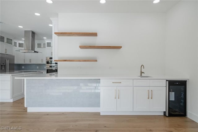 kitchen featuring white cabinets, sink, beverage cooler, and wall chimney range hood