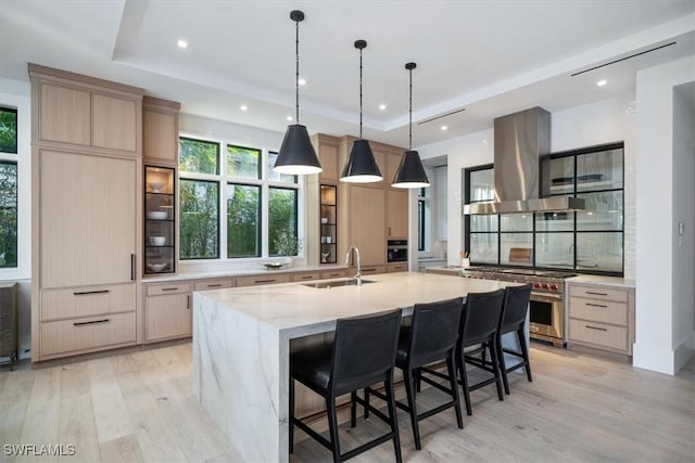 kitchen featuring a large island, light brown cabinets, high end stainless steel range oven, and extractor fan