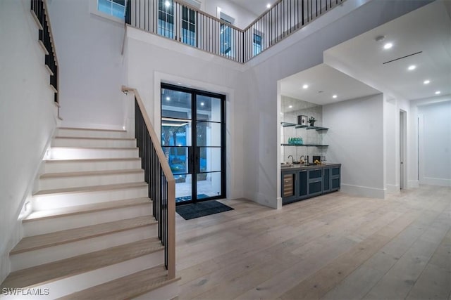 entrance foyer with light hardwood / wood-style floors and a towering ceiling