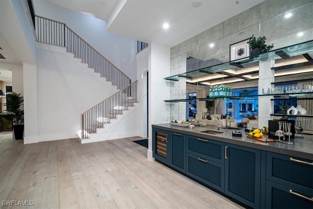 bar with blue cabinets, sink, and light hardwood / wood-style flooring