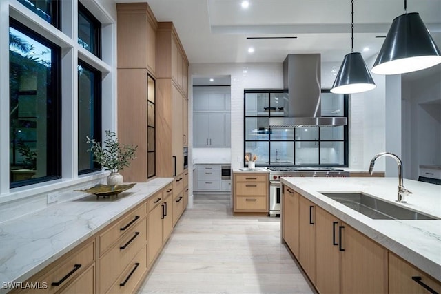 kitchen featuring pendant lighting, light brown cabinetry, wall chimney exhaust hood, and sink