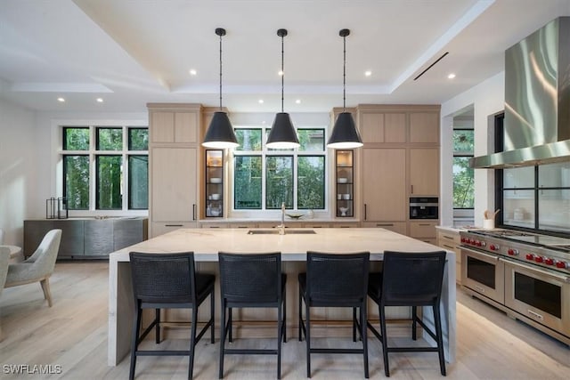 kitchen with extractor fan, light brown cabinetry, range with two ovens, and a large island