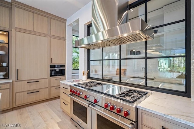 kitchen featuring double oven range, light brown cabinetry, and range hood