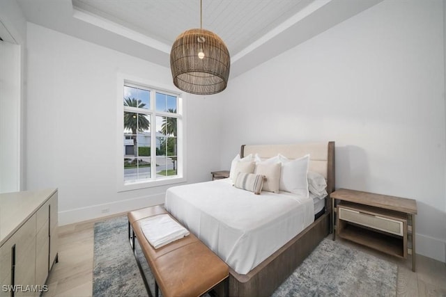 bedroom featuring a raised ceiling and light hardwood / wood-style flooring