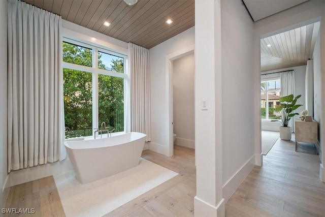 bathroom featuring a bathing tub, hardwood / wood-style floors, and wood ceiling