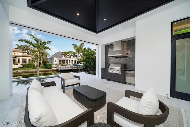 view of patio with an outdoor kitchen, area for grilling, a water view, and a swimming pool