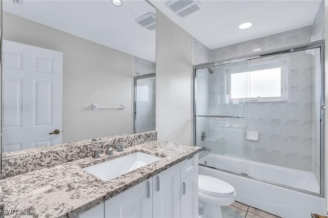 full bathroom featuring tile patterned flooring, vanity, bath / shower combo with glass door, and toilet