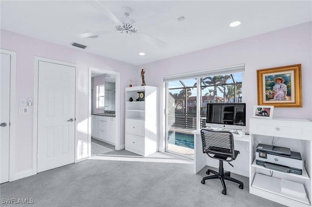 carpeted office space featuring ceiling fan