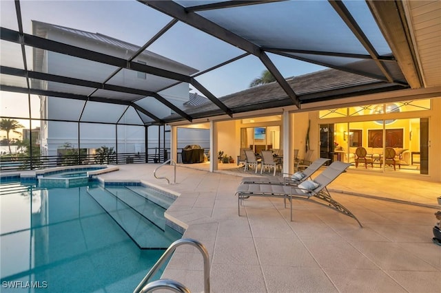 pool at dusk featuring an in ground hot tub, a patio, and a lanai