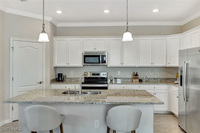 kitchen featuring pendant lighting, white cabinets, stainless steel appliances, and an island with sink