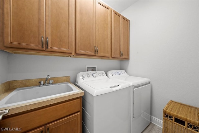 washroom with washer and clothes dryer, light hardwood / wood-style flooring, cabinets, and sink