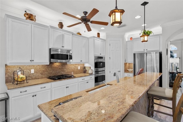 kitchen with decorative backsplash, appliances with stainless steel finishes, pendant lighting, white cabinetry, and a large island