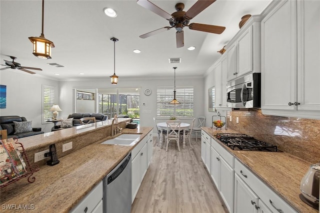 kitchen with pendant lighting, sink, white cabinets, and stainless steel appliances