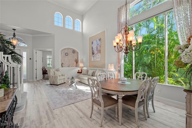 dining space featuring crown molding, light hardwood / wood-style flooring, a chandelier, and a high ceiling