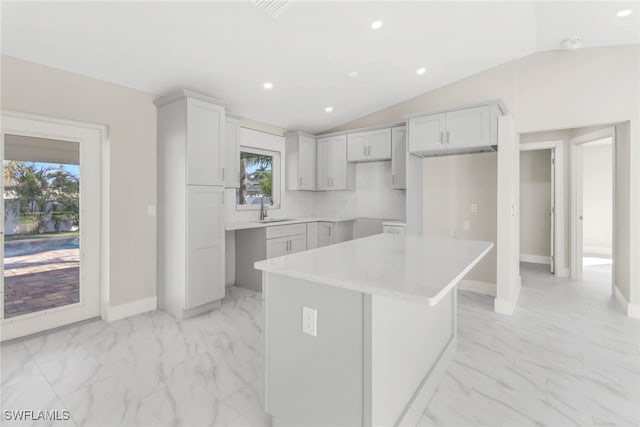 kitchen featuring vaulted ceiling, a kitchen island, plenty of natural light, and sink