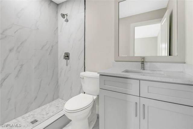 bathroom featuring tiled shower, vanity, and toilet