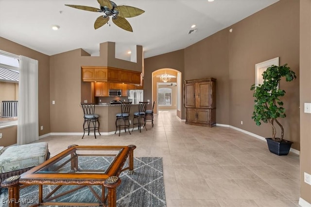 tiled living room with ceiling fan and high vaulted ceiling