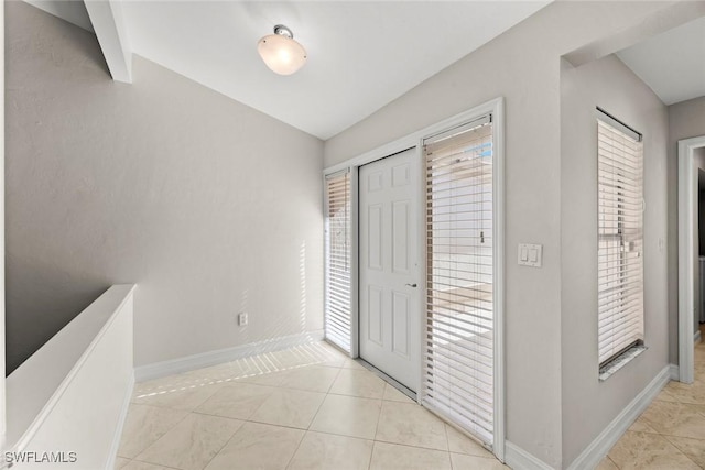 unfurnished bedroom featuring light tile patterned floors, multiple windows, and baseboards