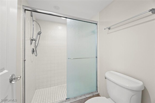 bathroom featuring toilet and a shower with door