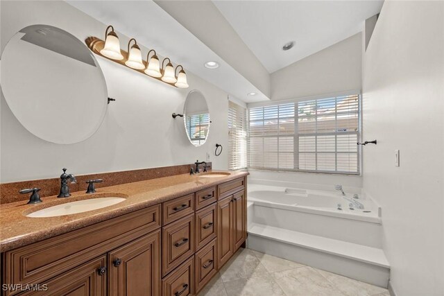 bathroom featuring a washtub, tile patterned floors, vanity, and vaulted ceiling