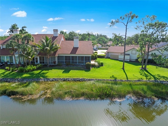 back of property with a water view and a lawn