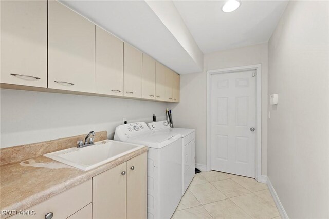 clothes washing area with cabinets, independent washer and dryer, light tile patterned floors, and sink