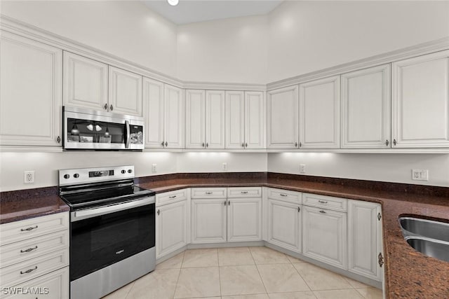 kitchen with white cabinetry, sink, stainless steel appliances, a high ceiling, and light tile patterned floors