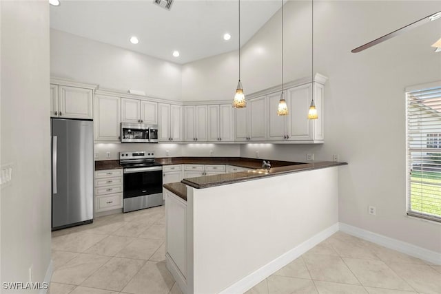 20110 Golden Panther Dr Unit 4, Estero, FL 33928 - kitchen featuring appliances with stainless steel finishes, dark countertops, a peninsula, light tile patterned flooring, and decorative light fixtures