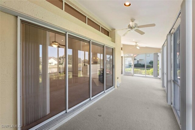 unfurnished sunroom with ceiling fan and vaulted ceiling