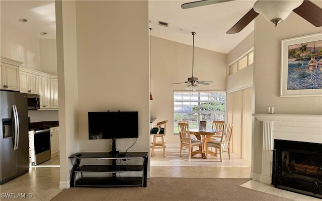 living area with high vaulted ceiling, visible vents, a fireplace with flush hearth, and light tile patterned flooring