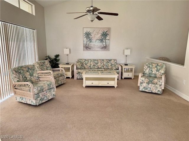 carpeted living area featuring ceiling fan, a high ceiling, and baseboards