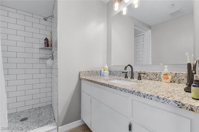 bathroom with a tile shower and vanity