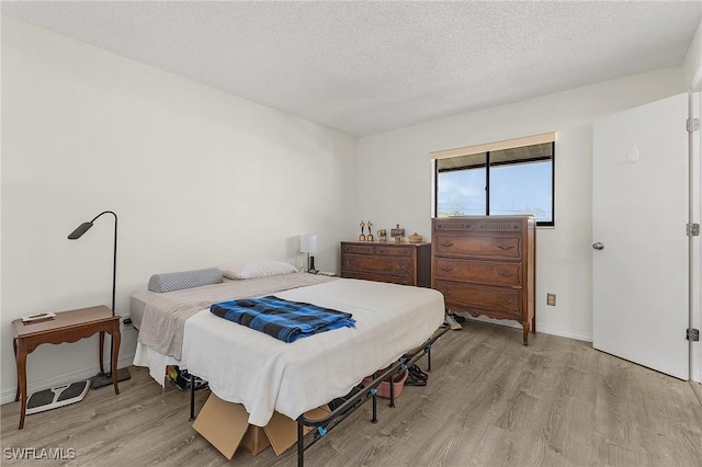 bedroom with a textured ceiling and light wood-type flooring