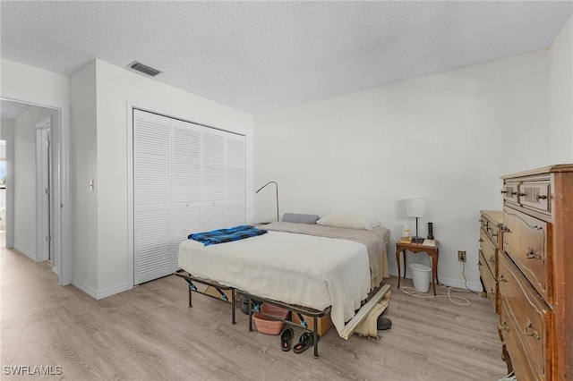 bedroom with a closet, light hardwood / wood-style floors, and a textured ceiling