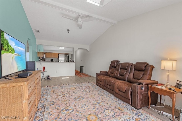 living room with light wood-type flooring, vaulted ceiling with beams, and ceiling fan