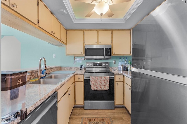 kitchen featuring stainless steel appliances, a raised ceiling, ceiling fan, sink, and light hardwood / wood-style flooring