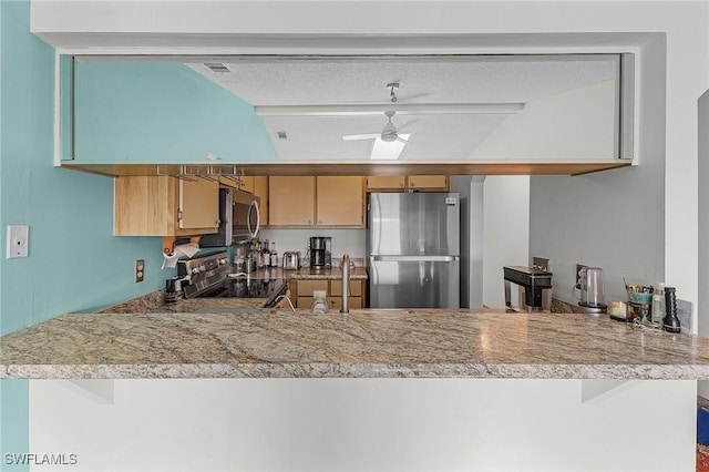 kitchen featuring kitchen peninsula, ceiling fan, stainless steel appliances, and a textured ceiling