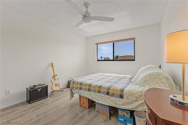 bedroom with ceiling fan, light hardwood / wood-style floors, and a textured ceiling