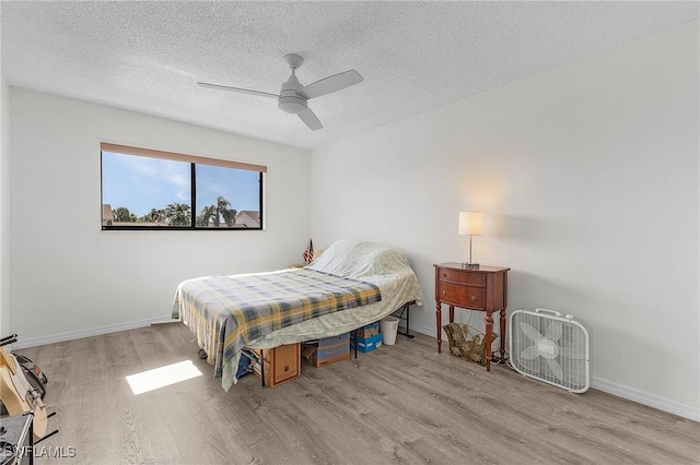 bedroom with ceiling fan, light wood-type flooring, and a textured ceiling