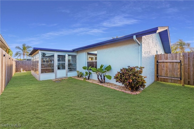 rear view of property featuring a lawn and a sunroom