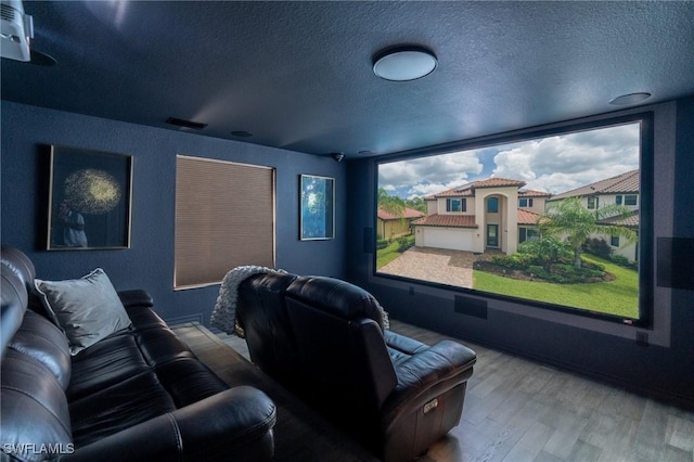 home theater room with a textured ceiling and hardwood / wood-style flooring