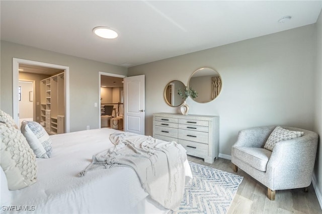 bedroom featuring a walk in closet, ensuite bathroom, and wood-type flooring