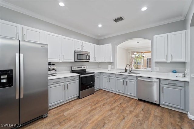 kitchen with gray cabinetry, stainless steel appliances, sink, light hardwood / wood-style flooring, and a notable chandelier