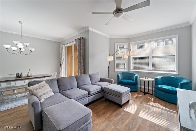 living room featuring ceiling fan with notable chandelier, crown molding, baseboards, and wood finished floors