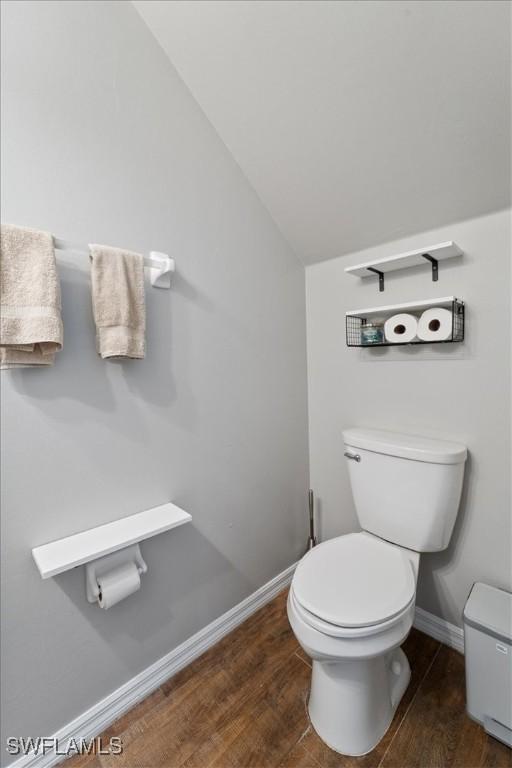 bathroom with vaulted ceiling, hardwood / wood-style flooring, and toilet