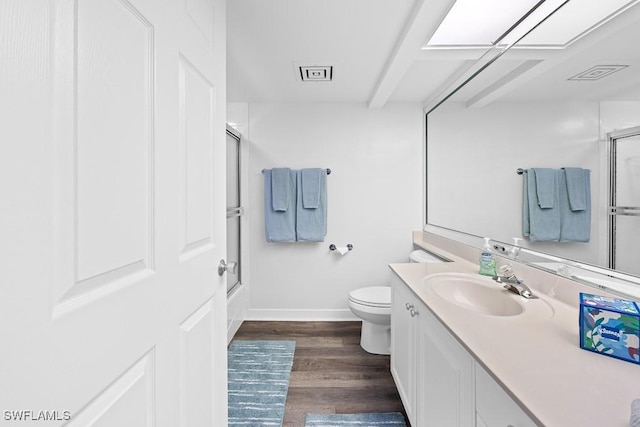 full bathroom with hardwood / wood-style floors, vanity, toilet, and combined bath / shower with glass door